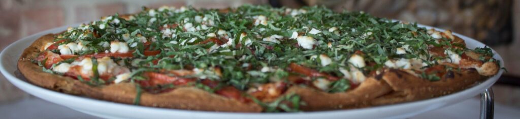 Margherita Pizza topped with fresh basil, goat cheese, and tomatoes.